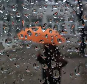 blurry orange umbrella seen through a wet window